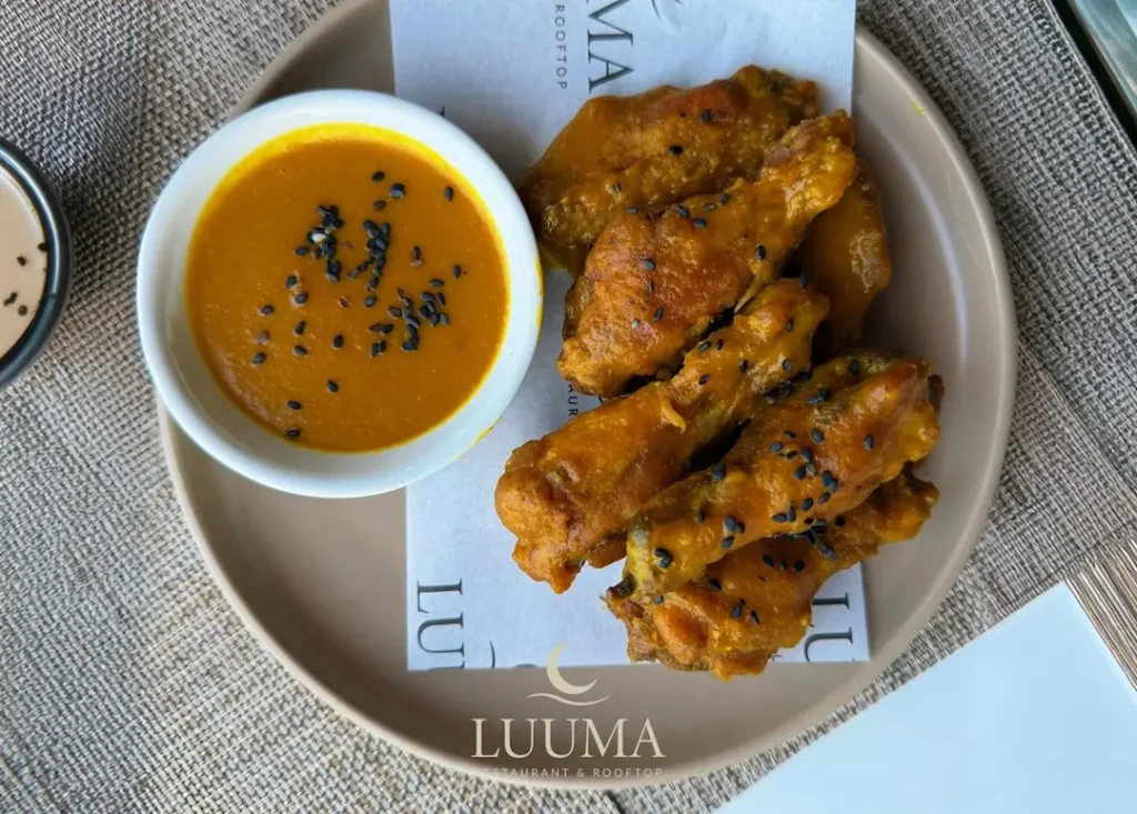 Alitas de pollo servidas en un restaurante de Manta con salsa y acompañamientos