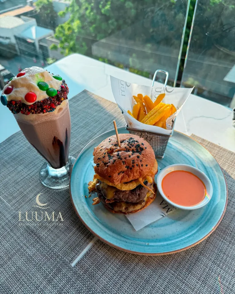 Hamburguesa gourmet servida en Luuma Rooftop en Manta con presentación atractiva y ambiente moderno