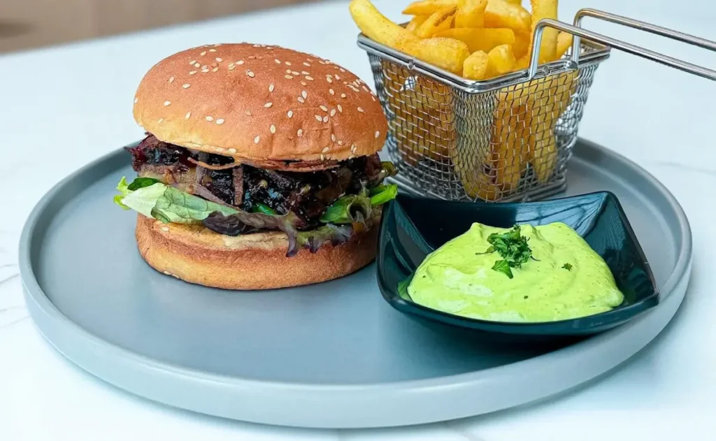 Hamburguesa con papas fritas servida en un restaurante de Manta con presentación gastronómica
